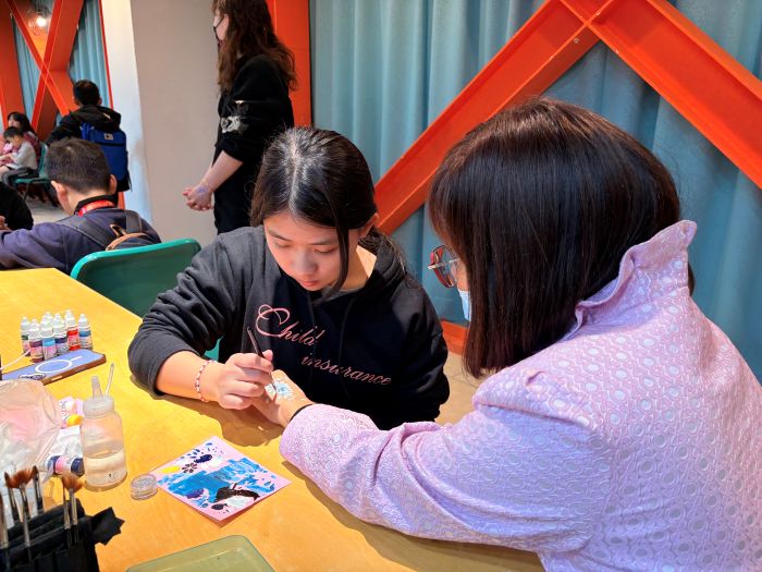 《圖說》莊敬高職美容科學生發揮專業，為愛心圍爐活動參加者進行人體彩繪體驗。〈社會局提供〉