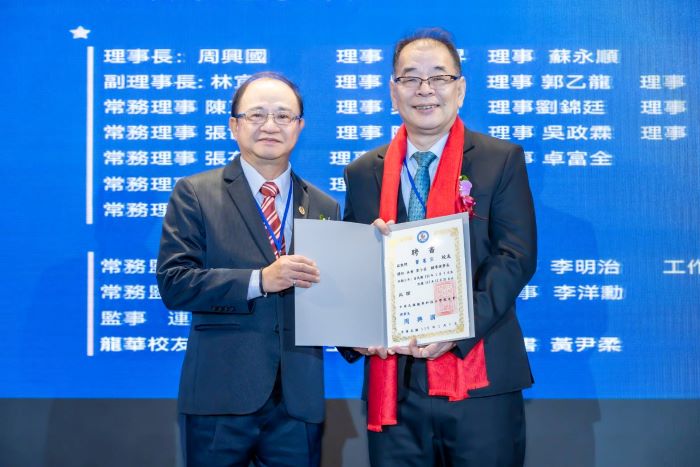 《圖說》新舊任理事長完成交接，新任第十屆理事長周興國（左）與卸任第九屆理事長竇憲宗（右）相互致意，象徵校友情誼的傳承。〈龍華科大提供〉