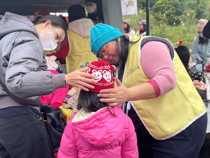《圖說》新北市淡水區關懷弱勢協會串連民間資源捐贈物資和善款，龍巖慈善基金會提供保暖衣物，協助民眾穿戴毛帽。〈社會局提供〉