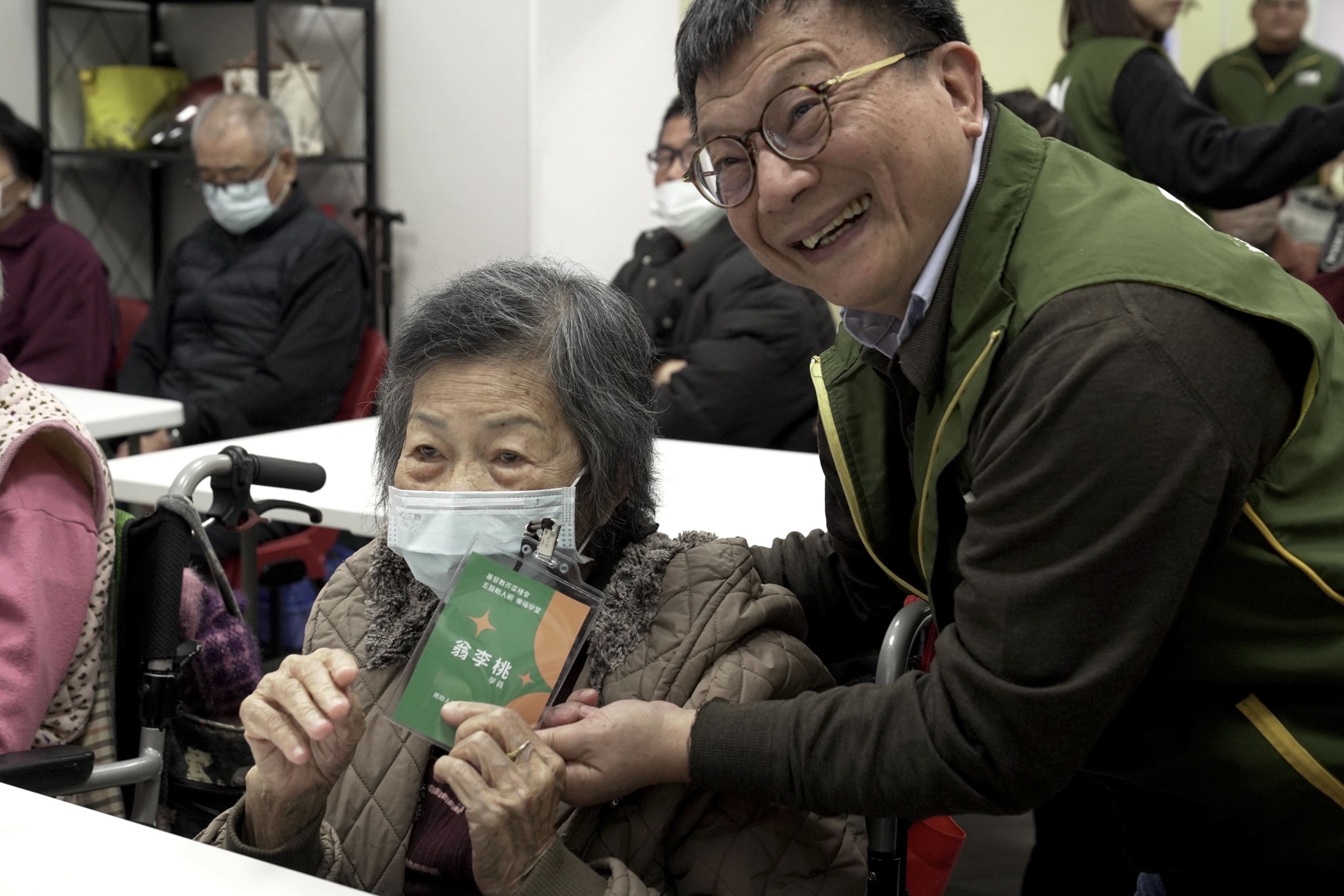 《圖說》芥菜種會執行長李肇家(右一)為五股助人網「樂福學堂」長者們掛學生證，給予愛的鼓勵。〈芥菜種會提供〉