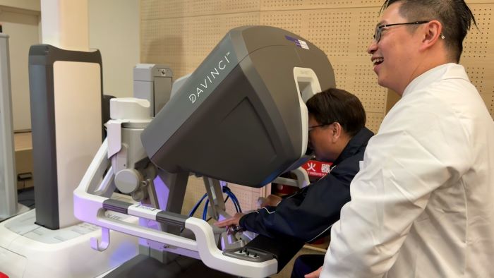 《圖說》劉和然體驗操作單孔達文西設備，劉忠一在旁說明協助。〈衛生局提供〉