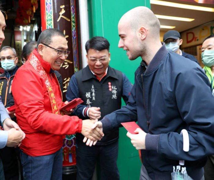 《圖說》侯友宜於慈惠宮親發馬年福袋分享喜氣,吸引外國友人排隊體驗台灣道地年味。〈民政局提供〉