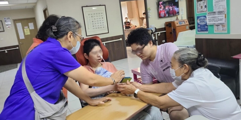 在社工和溫心天使的協助下阿宏的母親（中）和阿宏（右2）透過手機與在機構的小瑞視訊