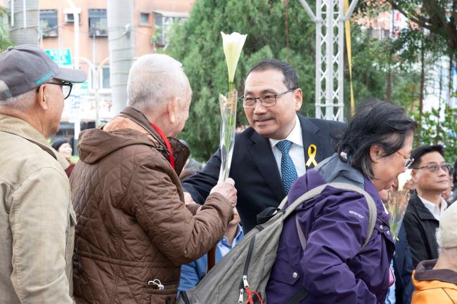 《圖說》侯友宜市長逐一遞送鐵炮百合給受難者家屬獻花,撫慰受難者心靈。〈民政局提供供〉