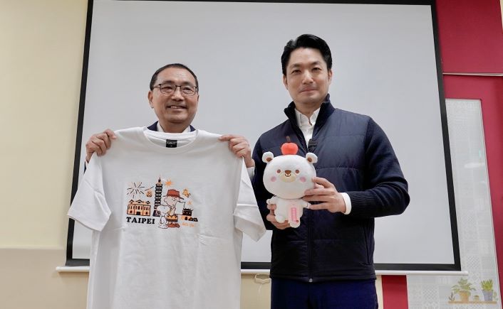 《圖說》侯友宜市長致贈「新北愛小孩吉祥物 熊果」予蔣萬安市長，象徵雙北攜手守護孩子「平安長大」，蔣萬安則致贈史努比T恤、帽子等聯名周邊〈社會局提供〉