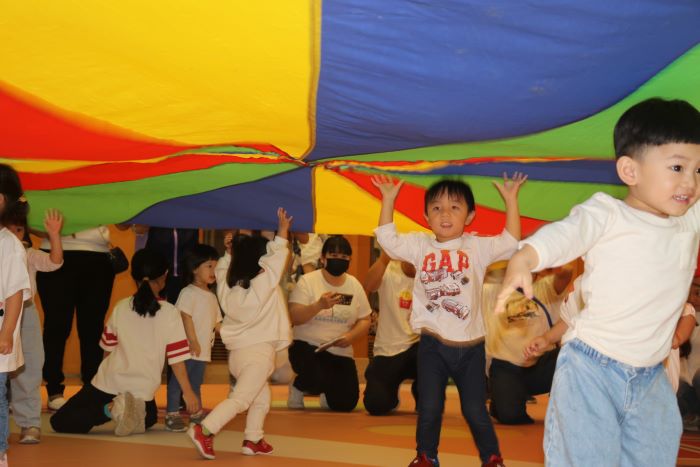 130公托串聯63親子館 新北兒童月動玩童趣會熱鬧開跑 41 《圖說》小朋友躲在氣球傘下玩。〈社會局提供〉