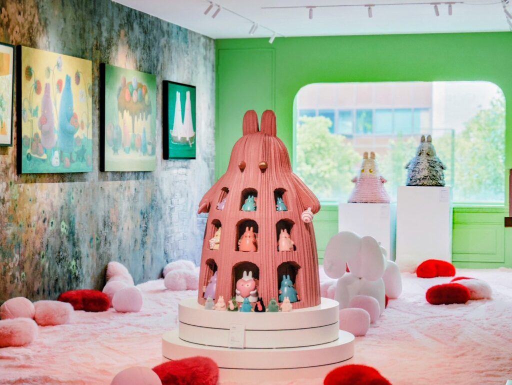 04四樓另一翼展區以鮮明飽和的翠綠牆面，搭配林天祿立體Momo兔雕塑形成強烈對比；畫作