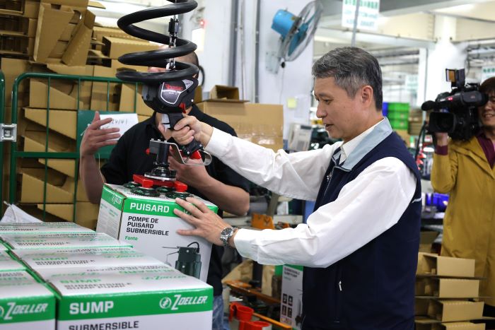 《圖說》陳瑞嘉體驗真空吸盤搬運設備，將重達16公斤的產品輕鬆移動至棧板上。〈勞工局提供〉