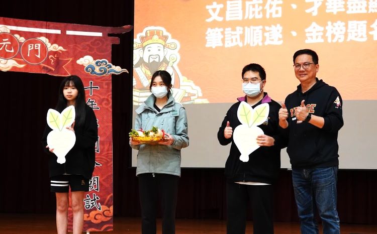 《圖說》鶯歌工商校長帶領學生,以蘿蔔、包子、粽子寓意「好彩頭、包中、包粽」展現校園陪伴。〈教育局提供〉