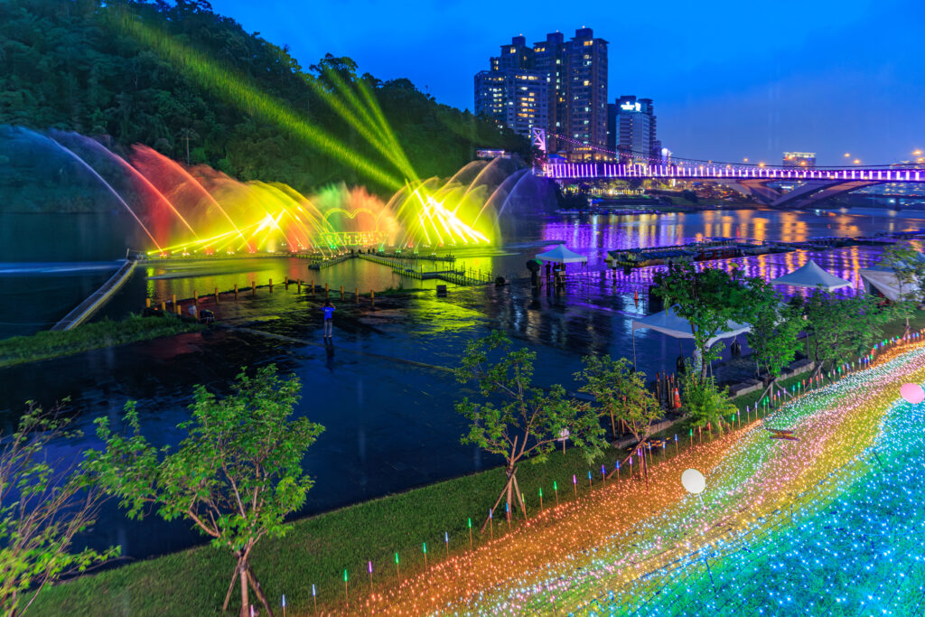 夜幕降臨，碧潭水域化身流光舞台，七彩水柱隨音樂律動綻放，與吊橋燈飾及岸邊光廊交