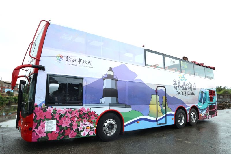 《圖說》移動的觀景台！青春山海線景觀雙層巴士車身吸睛，彩繪融合野柳女王頭、富貴角燈塔與淡江大橋，滿載新北濱海意象。〈觀旅局提供〉