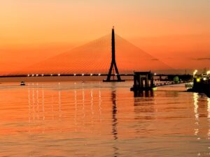 《圖說》夕照映照淡江大橋與水岸景致，橘紅天色與橋體光影交織，呈現迷人河口風光。〈觀旅局提供〉